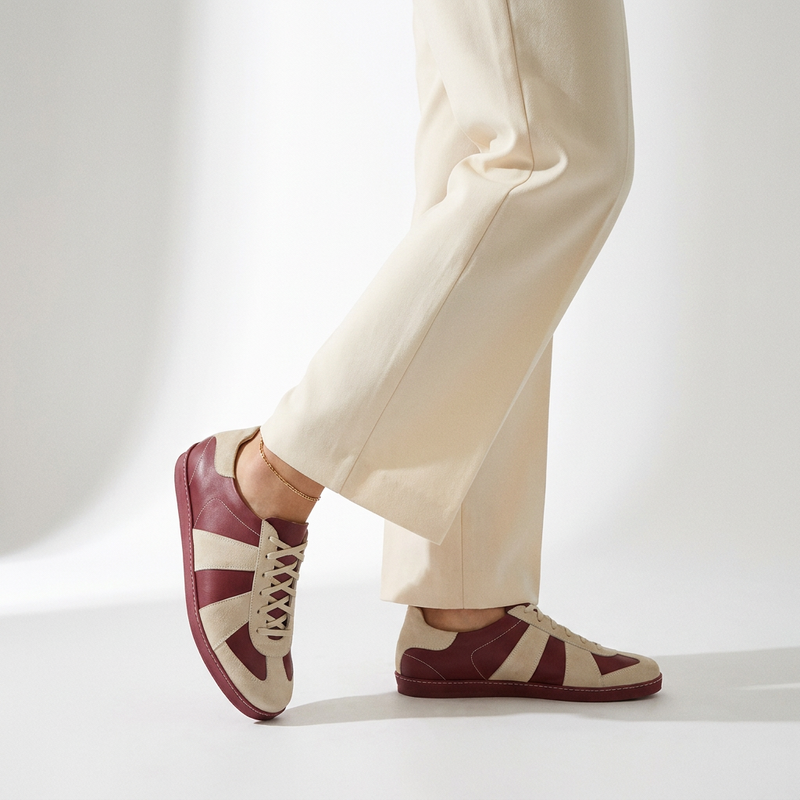 Person wearing maroon and beige shoes with white pants on a light background